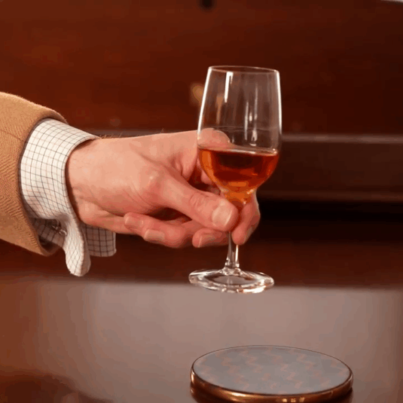 Fortified Wine Glass Proper Handling Hand pinching the mid-stem of a small fortified wine glass, holding it delicately with two fingers.