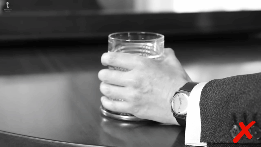  Man gripping lowball glass incorrectly by wrapping full hand around the glass