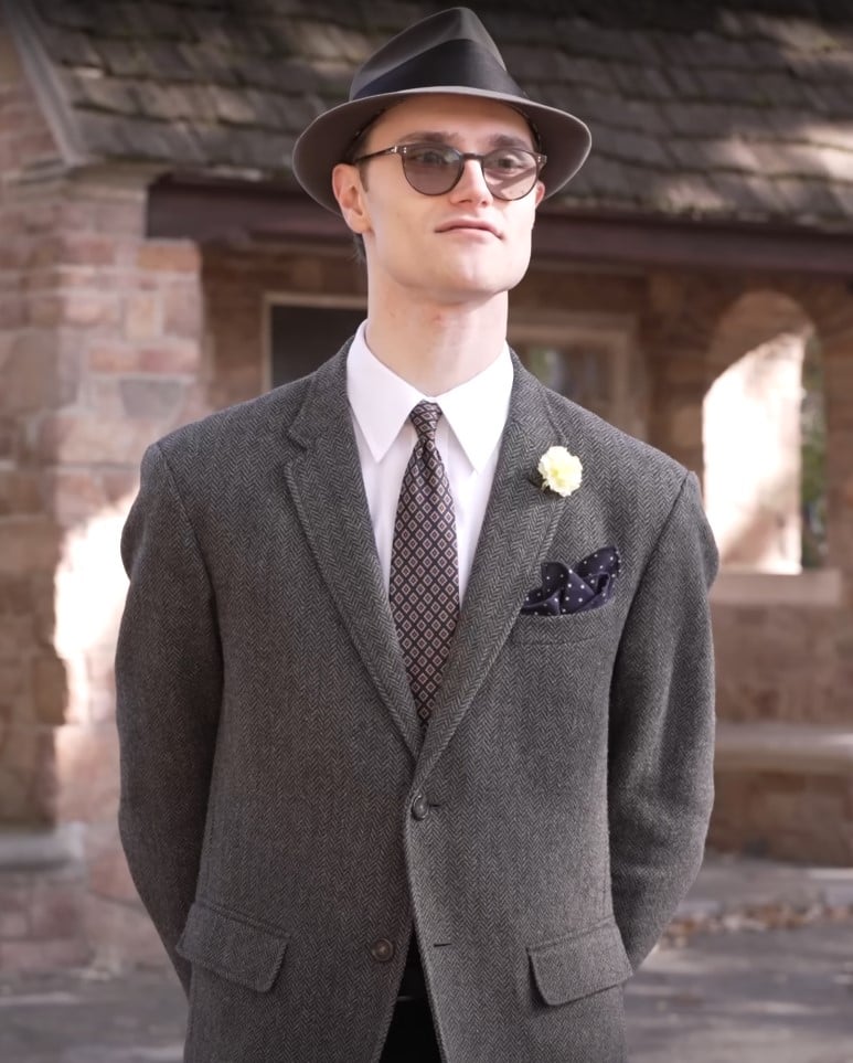 gray herringbone jacket fedora pocket square Preston in gray herringbone jacket with patterned tie, navy polka-dot pocket square, yellow boutonniere, and fedora hat.