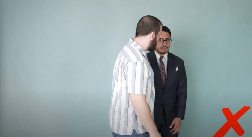 Man in striped shirt nearly colliding with suited man who stopped suddenly.