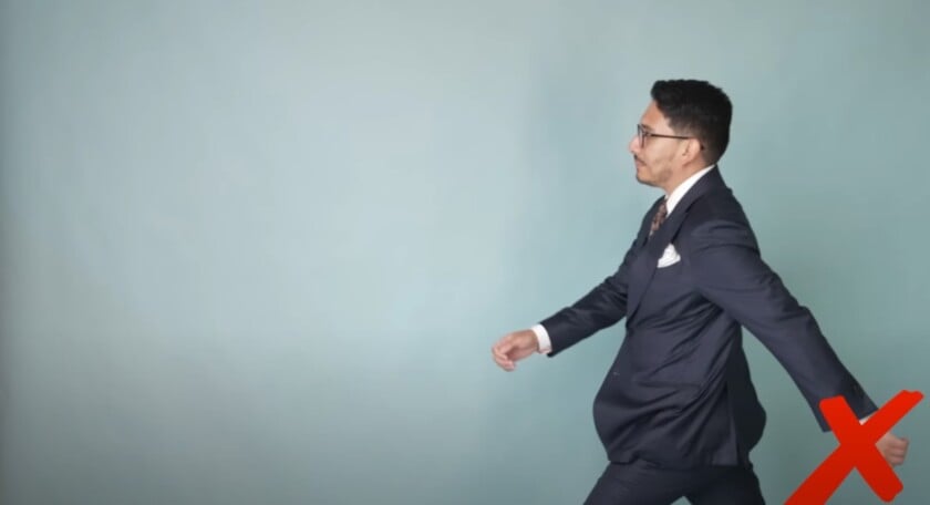 Man in suit walking with arms swinging too widely