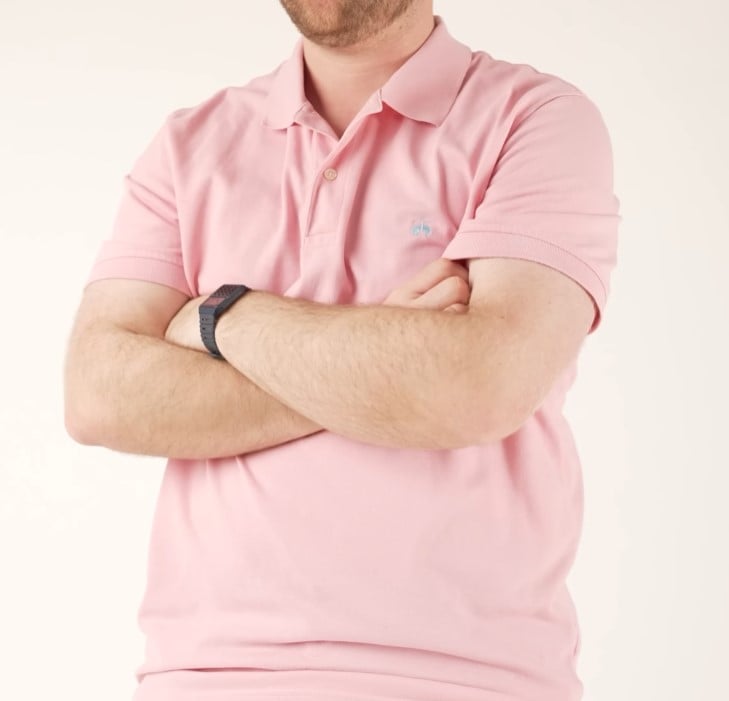 Gentleman Salmon Pink Polo Shirt A man with his arms crossed, modeling a light salmon pink short-sleeve polo shirt.