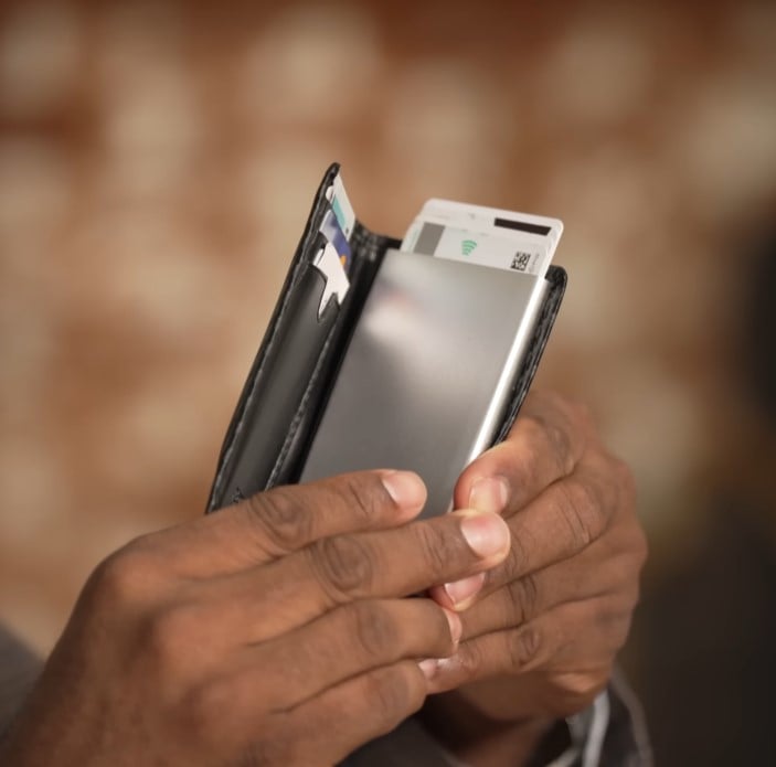 slim wallet with pop up card mechanism Close-up of hands holding a black slim wallet featuring a silver metal case with a pop-up card ejection mechanism.