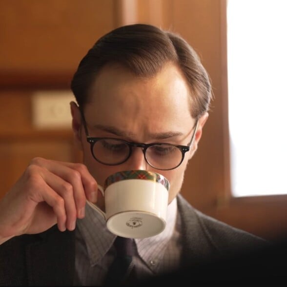 Man in classic attire sipping tea from a teacup