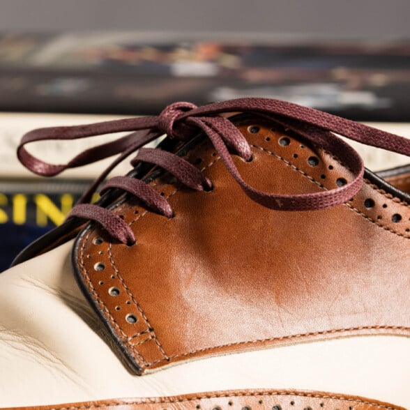 A pair of tan and cream spectators worn with flat burgundy dress shoelaces from Fort Belvedere.