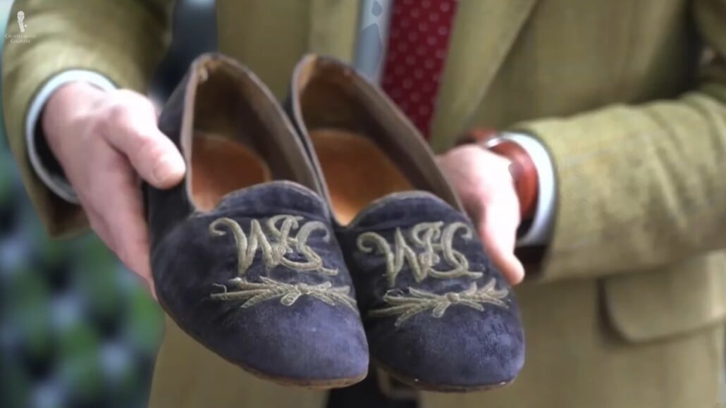 Hands holding a pair of monogrammed Albert Slippers.