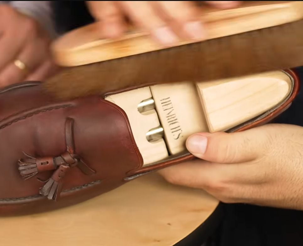 vigorously brushing a brown shoe