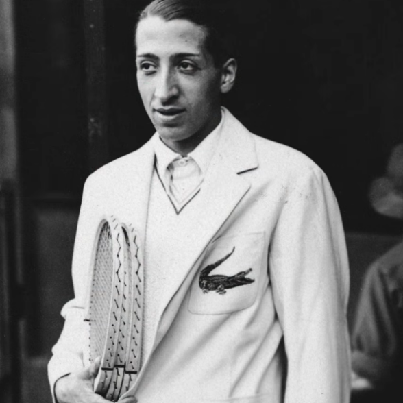 René Lacoste Crocodile Blazer Black and white photograph of René Lacoste holding a tennis racket in a white tennis blazer with the initials Crocodile emblem on the chest pocket