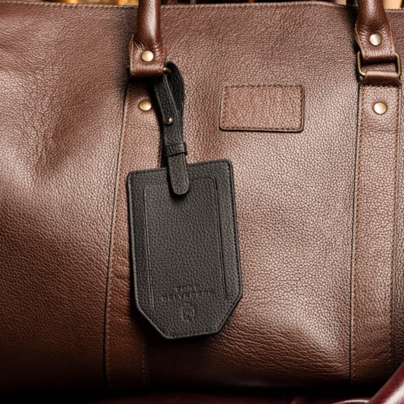 Fort Belvedere Black Togo Leather luggage tag attached to a brown leather bag