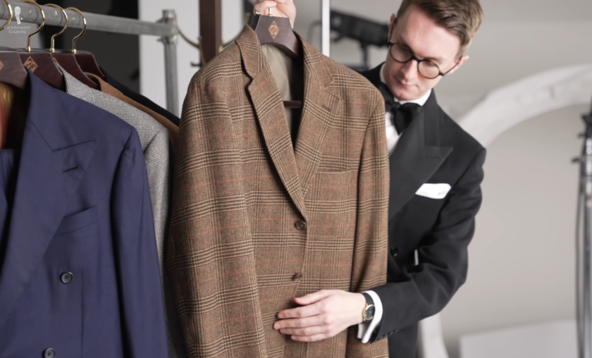 Brown Glen Plaid Check Jacket Patch Pockets Jack Collins holding up a brown Glen plaid check jacket with patch pockets on a clothing rail, with the navy and gray suits hanging alongside