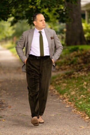Stancliffe Corduroy Flat Front Trouser In Dark Olive Fort Belvedere R5 9230 Raphael sporting the Dark Olive corduroy trousers with his hands tucket inside the trouser pockets.