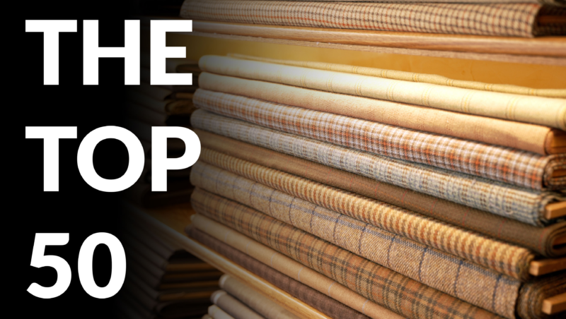 Stacked bolts of checked, plaid, and tweed suiting fabrics beside bold "The Top 50" title text, the banner for a guide to menswear fabrics