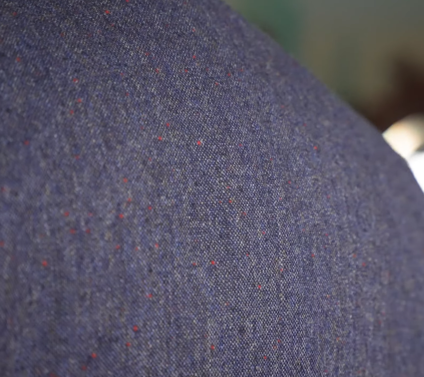 Donegal Tweed Blue Nepps Close Up Close-up of blue-purple Donegal tweed showing red and dark nepps flecked through the woven base