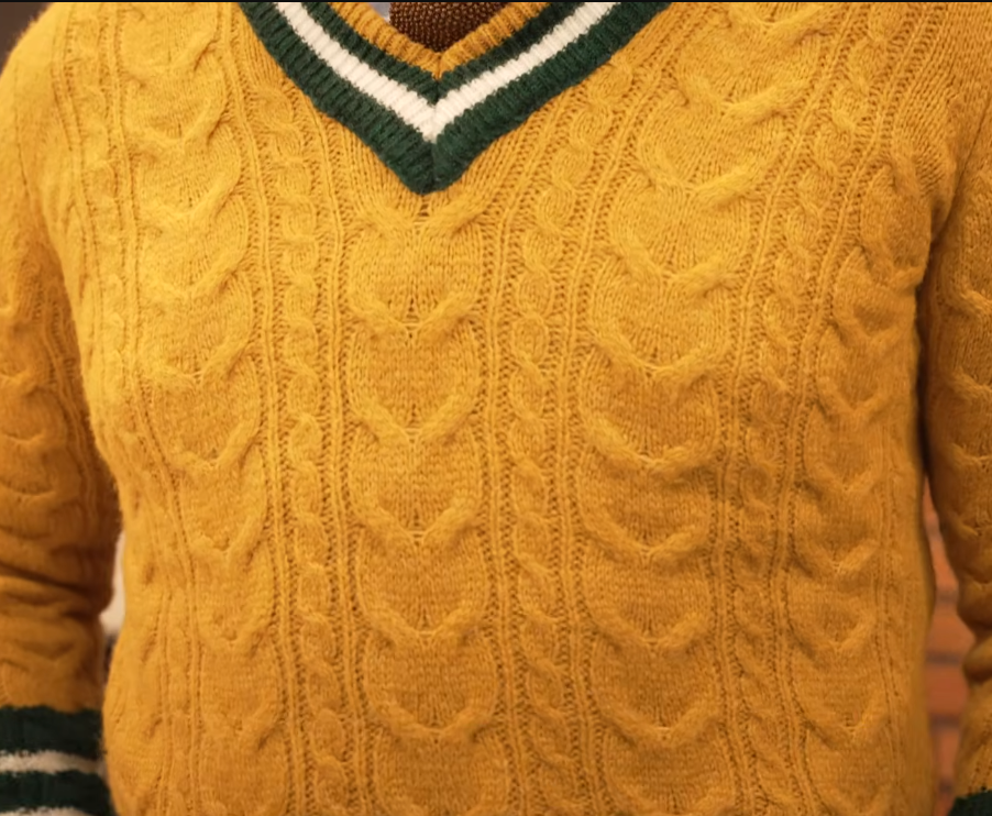 Shetland Mustard V Neck Sweater Mustard cable-knit V-neck sweater with green and white tipping, worn over a shirt and tie