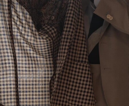 Detail shot of layered check and houndstooth sport coats in brown, tan, and cream tones